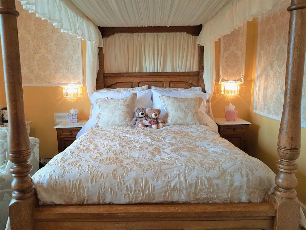 twee teddyberen op een bed bij Min y Don Guest House in Llanfairfechan