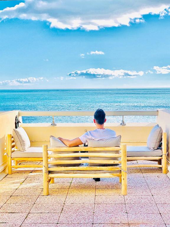 un homme assis sur un banc et regardant l'océan dans l'établissement Résidence la Corniche appartement rénové de 66m2 pleine vue mer!, à Sète