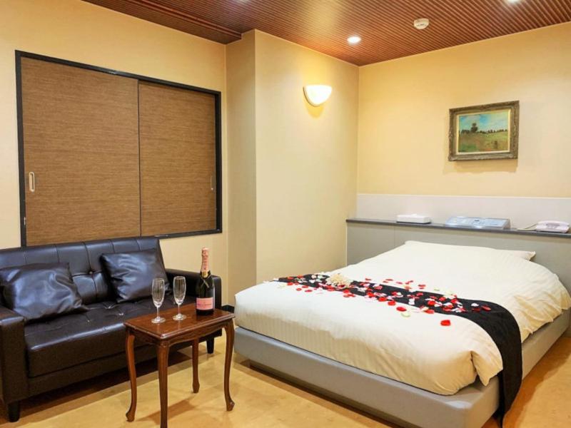 Hotel NewMie (Adult Only) في طوكيو: غرفة نوم بسرير واريكة وطاولة