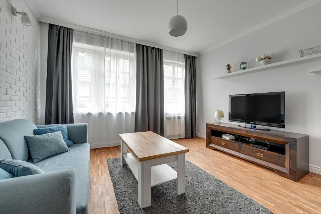 a living room with a blue couch and a tv at Willa Morska Superior by Grand Apartments in Sopot