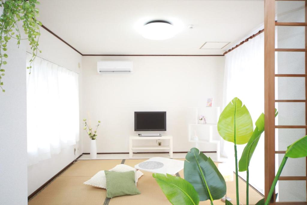 a living room with a tv and plants at Higashiomi Large House in Higashiomi
