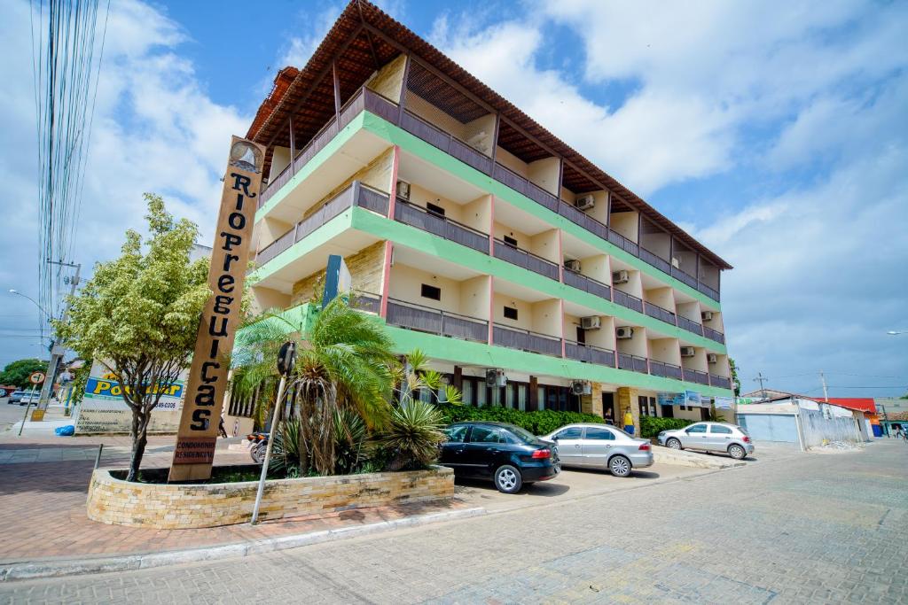 ein Hotelgebäude mit auf einem Parkplatz geparkt in der Unterkunft Hotel Rio Preguiças in Barreirinhas