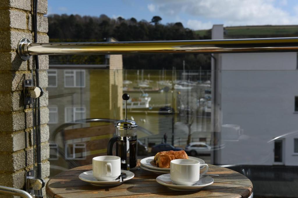 a table with two cups of coffee and croissants on a balcony at Dartside 1 in Dartmouth