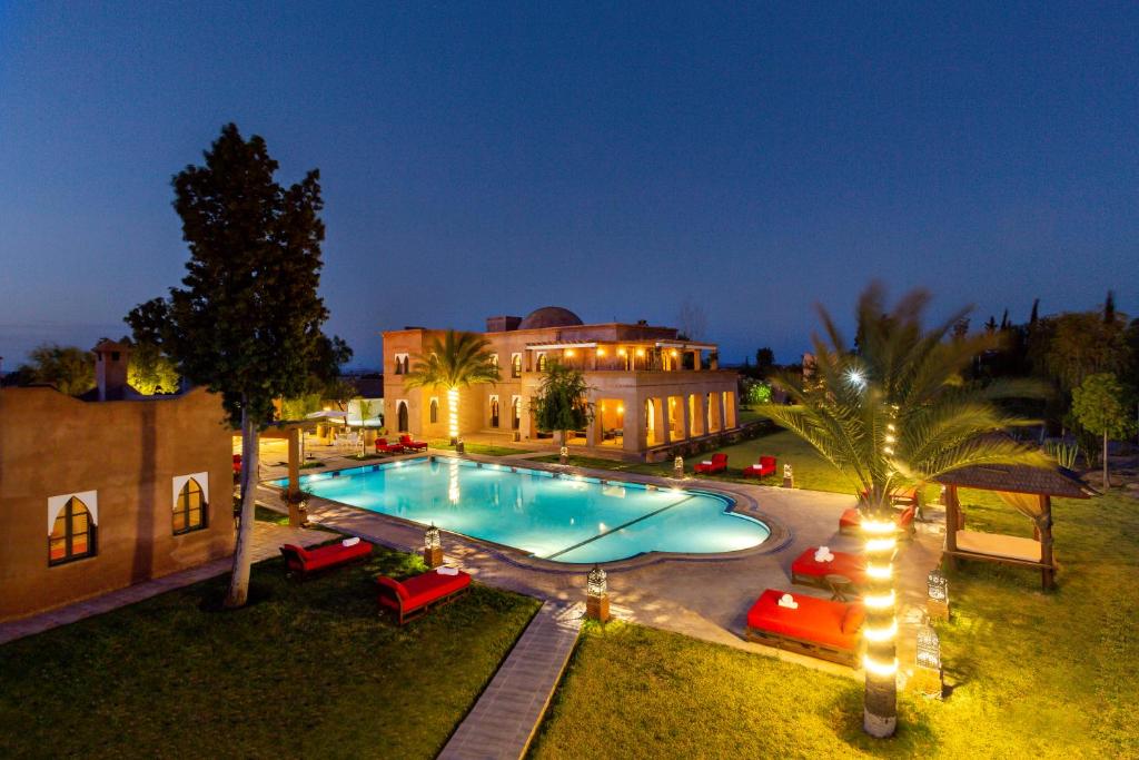 a large swimming pool in front of a building at night at Villa Thaifa in Marrakesh