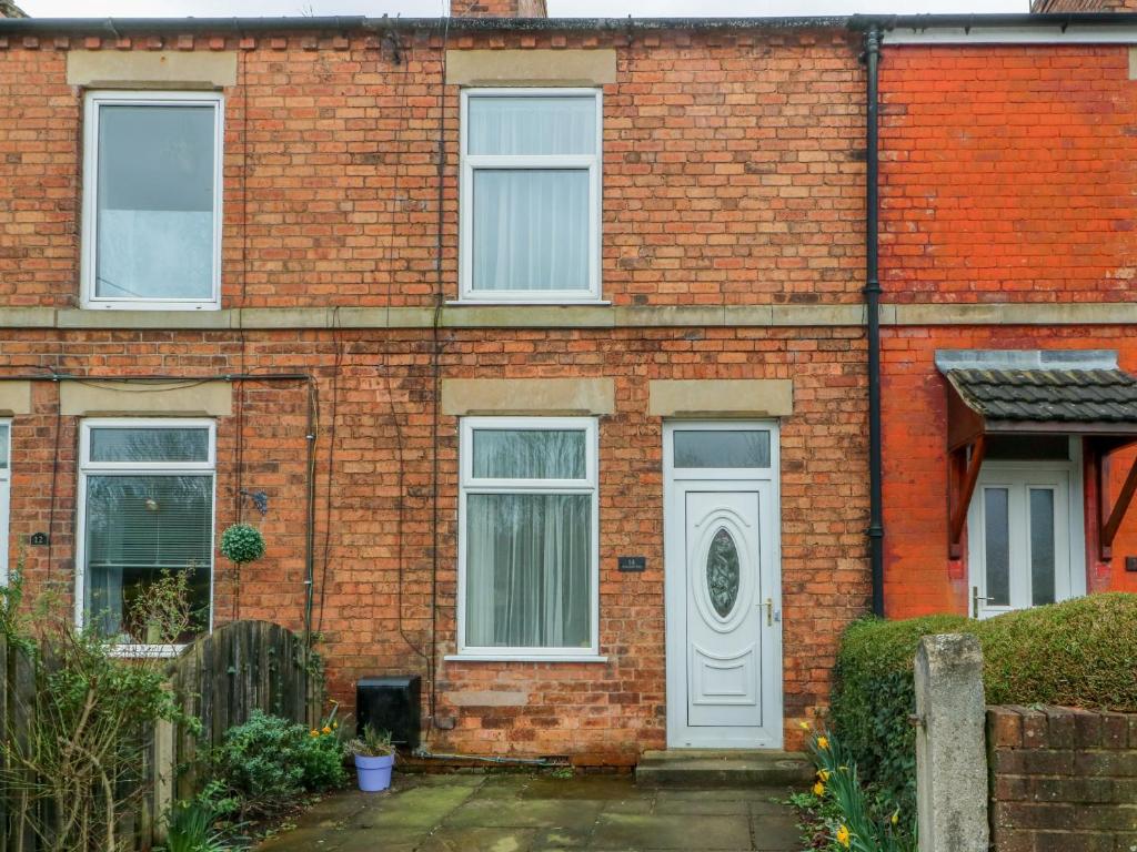 una casa de ladrillo rojo con puerta blanca en Hazelmere Cottage en Worksop