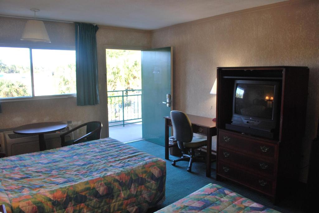 Habitación de hotel con cama, TV y escritorio. en Best Motel Lakeland, en Lakeland
