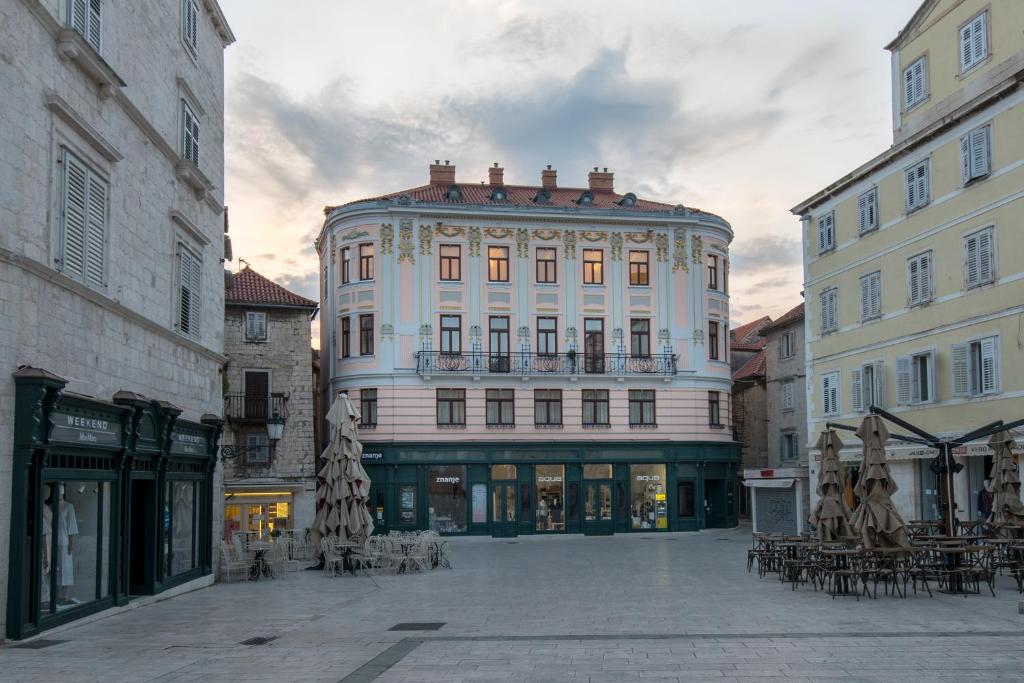 duży biały budynek ze stołami i krzesłami przy ulicy w obiekcie Central Square Heritage Hotel w Splicie