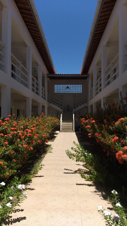 a hallway of a building with red flowers at Pousada Planeta Guarajuba in Guarajuba