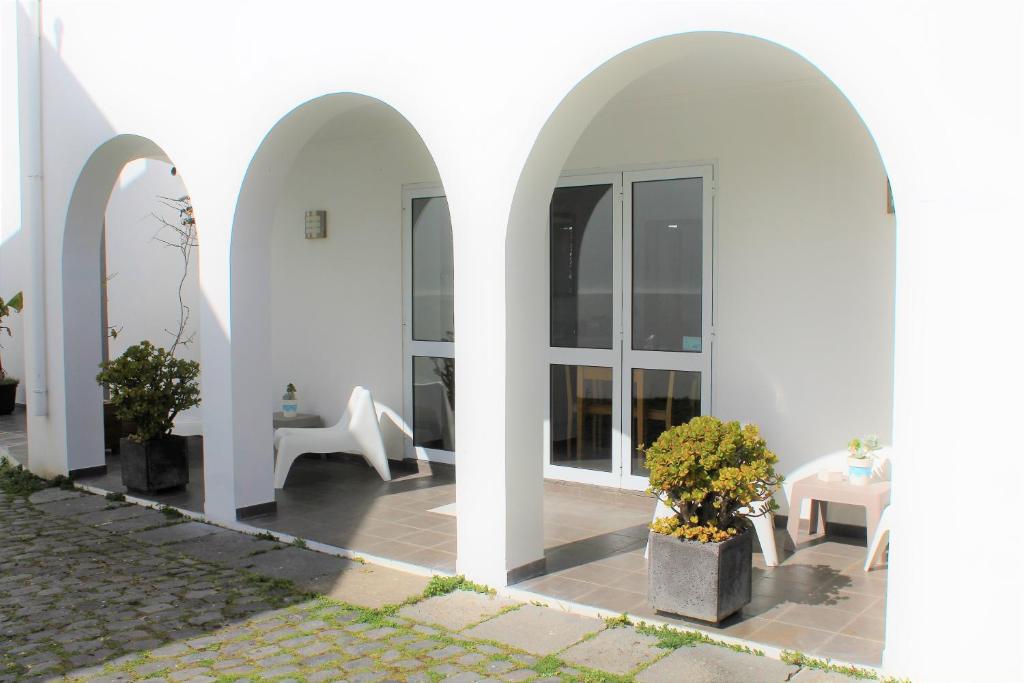 a white house with arches and a table and chairs at Hotel Arcanjo in Rosário-Lagoa