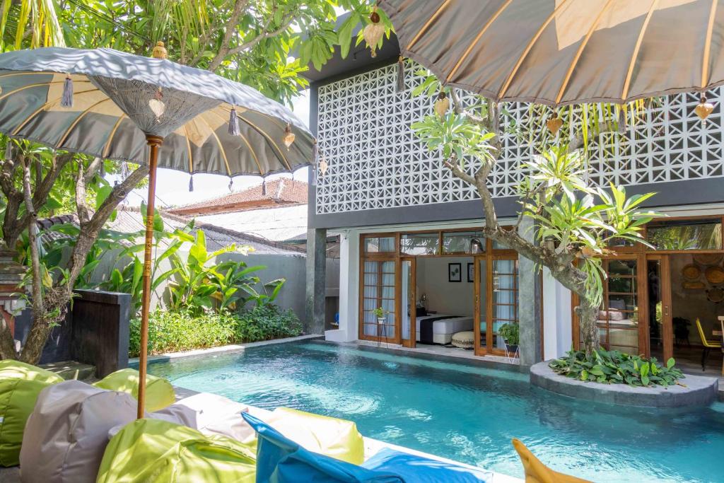 a swimming pool with two umbrellas next to a house at Interconnection Hostel in Kuta