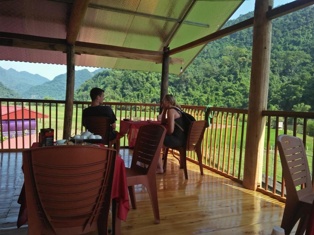 Ein Mann und eine Frau sitzen an einem Tisch auf einer Veranda. in der Unterkunft Tran Xuan Homestay Ba Be Village in Ba Be18