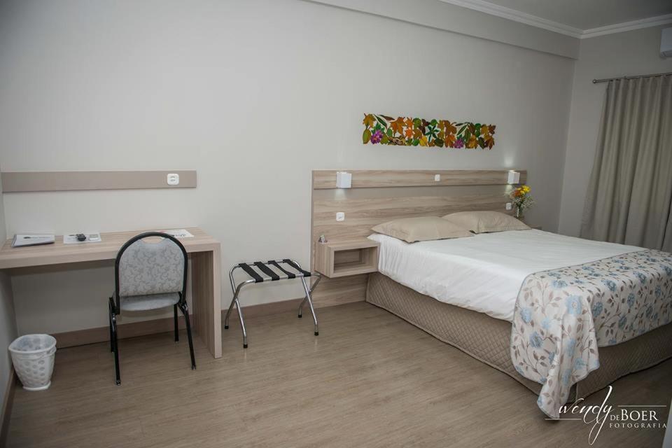 a bedroom with a bed and a desk and a chair at Hotel De Klomp in Carambeí