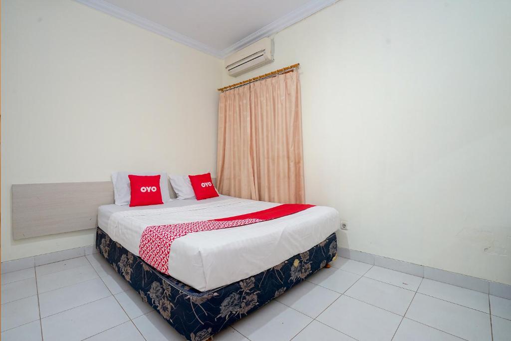 een slaapkamer met een bed met rode kussens erop bij OYO 2025 Wisma Musdalifa in Palembang