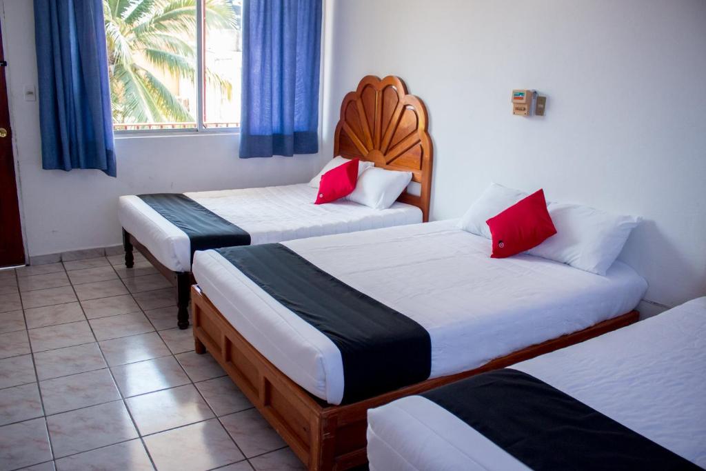 a hotel room with two beds and a window at Hotel Adelita in Zihuatanejo