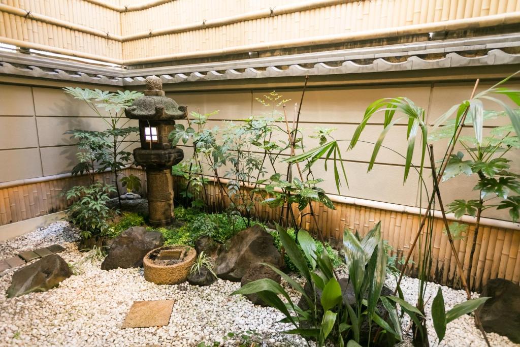 a garden with a water fountain in a fence at Kyonoyado Kagihei in Kyoto