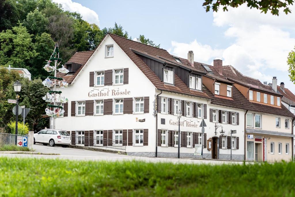 un grand bâtiment blanc avec un toit marron dans l'établissement Hotel Gasthof Rössle, à Weingarten