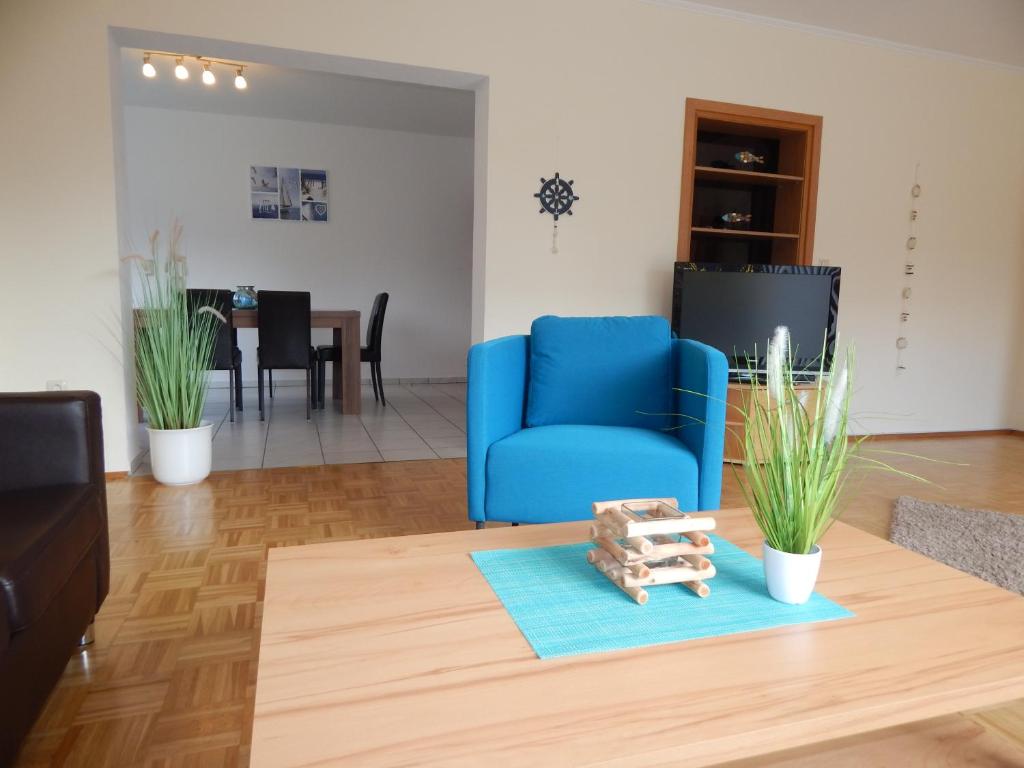 uma sala de estar com uma cadeira azul e uma mesa em Ferienhaus "NordseeZeit" em Burhave