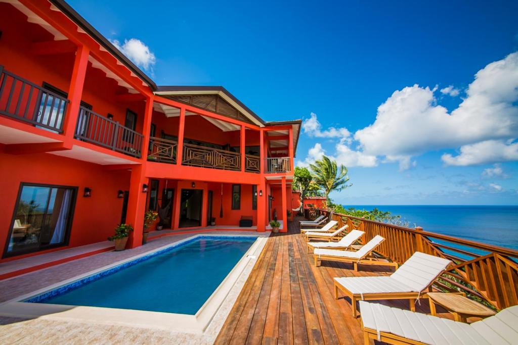 a house with a swimming pool next to the ocean at Villa On The Bay - Relaxed Elegance in Marigot Bay
