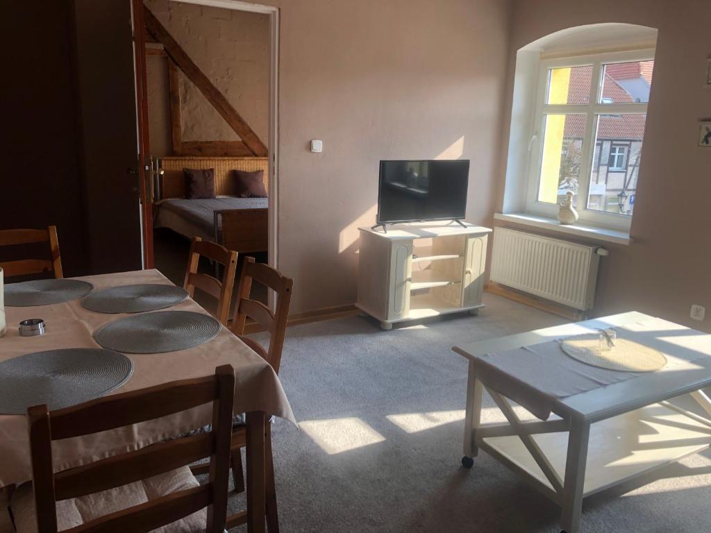 salon ze stołami, telewizorem i łóżkiem w obiekcie Apartament przy Rynku 2 w mieście Połczyn-Zdrój