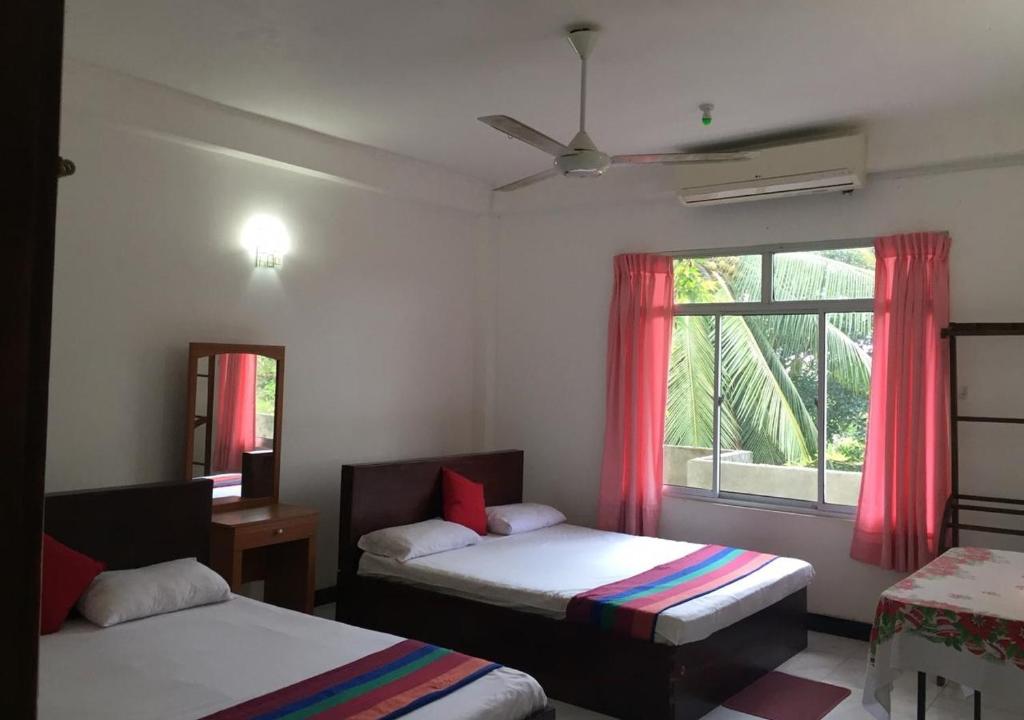 sypialnia z dwoma łóżkami i oknem w obiekcie Pleasure Island Holiday Home w mieście Dambulla