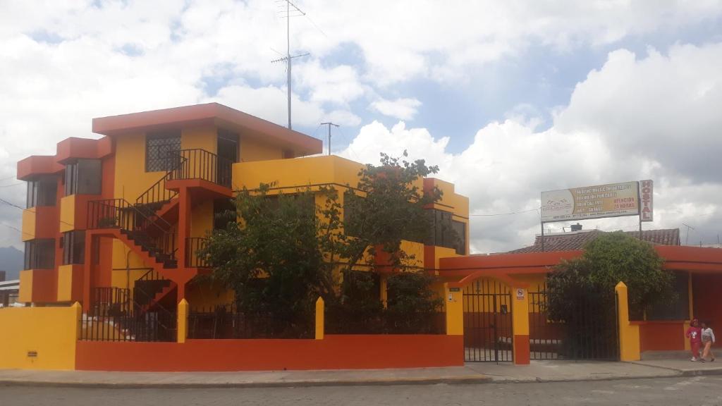 ein gelbes und rotes Gebäude auf der Straßenseite in der Unterkunft Hostal Miraflores Cayambe in Cayambe