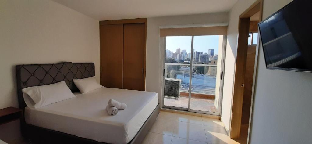 um quarto com uma cama e uma grande janela em Apartahotel Plaza de ángel 74 em Barranquilla