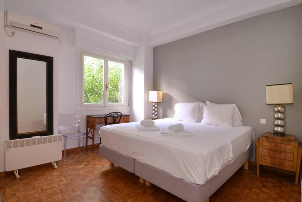 una camera bianca con un grande letto e uno specchio di Thiseio, a vintage apartment ad Atene