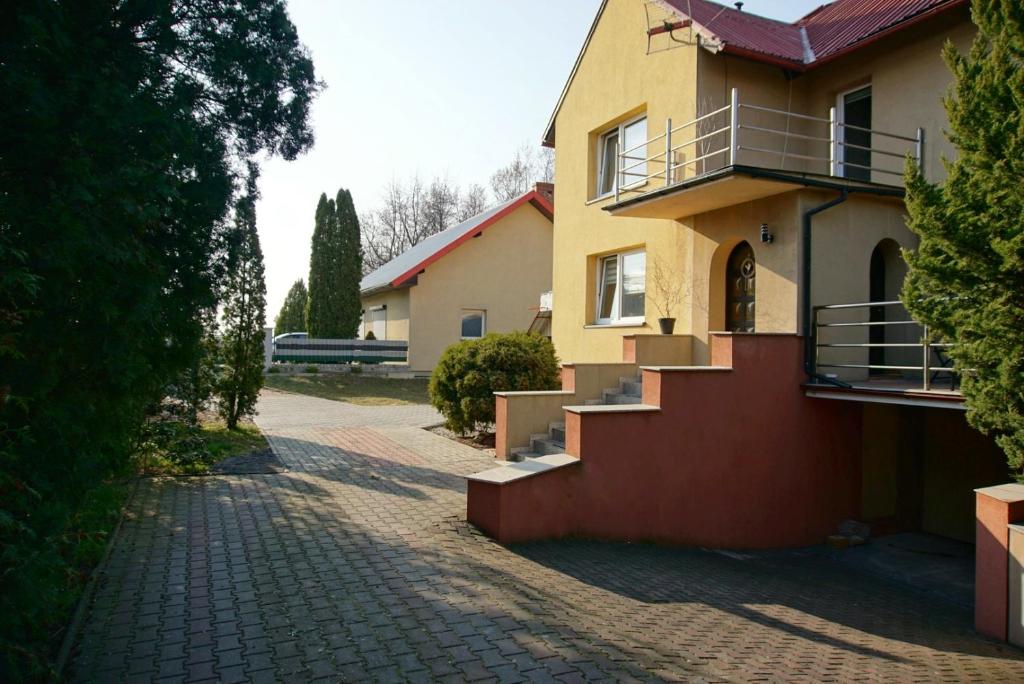żółty dom ze schodami na ceglanej drodze w obiekcie Pokoje gościnne w mieście Stradunia