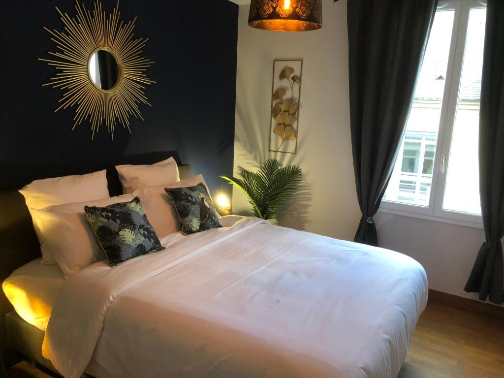 a bedroom with a large white bed with pillows at Au Coeur du Marché 4 étoiles in Fécamp