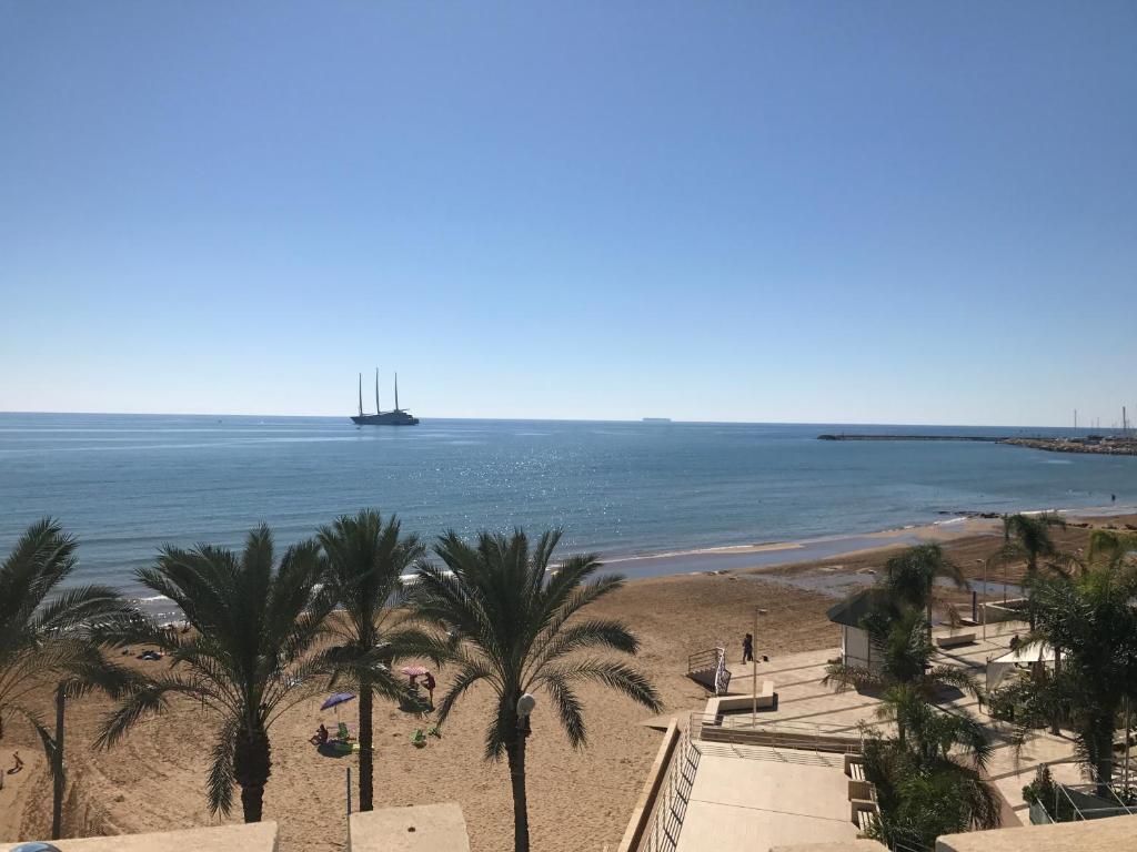 a beach with palm trees and a ship in the water at DELPOSTO Marina di Ragusa DS in Marina di Ragusa