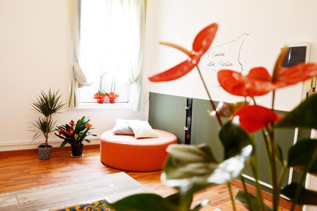 uma sala de estar com um repousa-pés laranja e algumas plantas em I Colori della SICILIA em Caltagirone