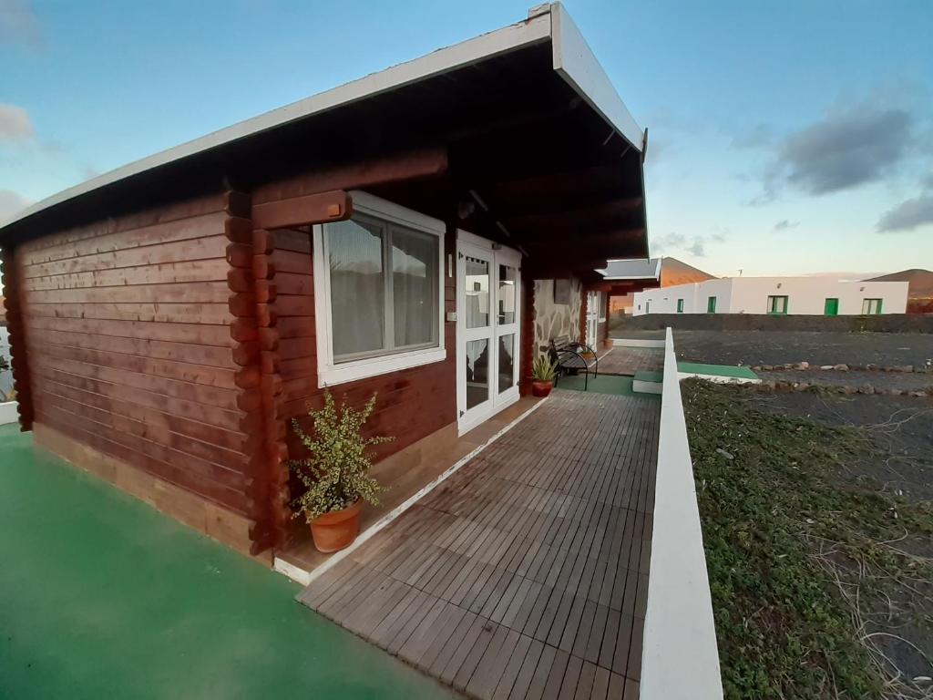 a small house with a wooden deck at Cabañas Volcán Capellania in Tinguatón