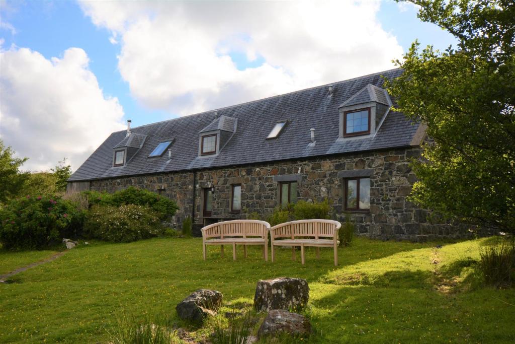 a stone house with two benches in front of it at Diubaig House in Edinbane