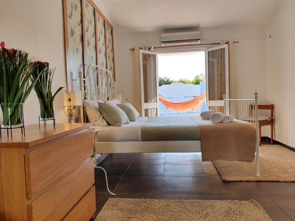 um quarto com uma cama e uma grande janela em Moradia Familiar Piscina 5min Praia by HOST-POINT em Charneca