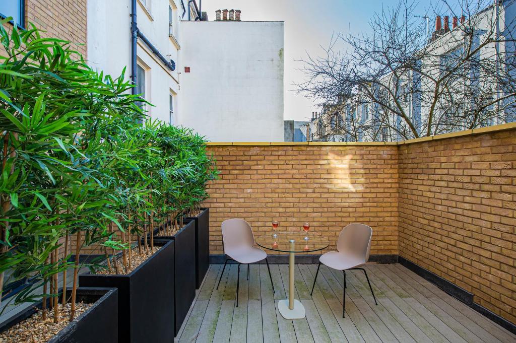 a patio with two chairs and a table on a brick wall at Q Square by Supercity Aparthotels in Brighton & Hove