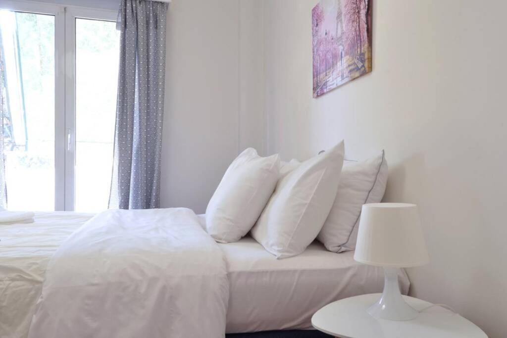 a white bed with white pillows and a window at Kerameikos, a lovely apartment in Athens