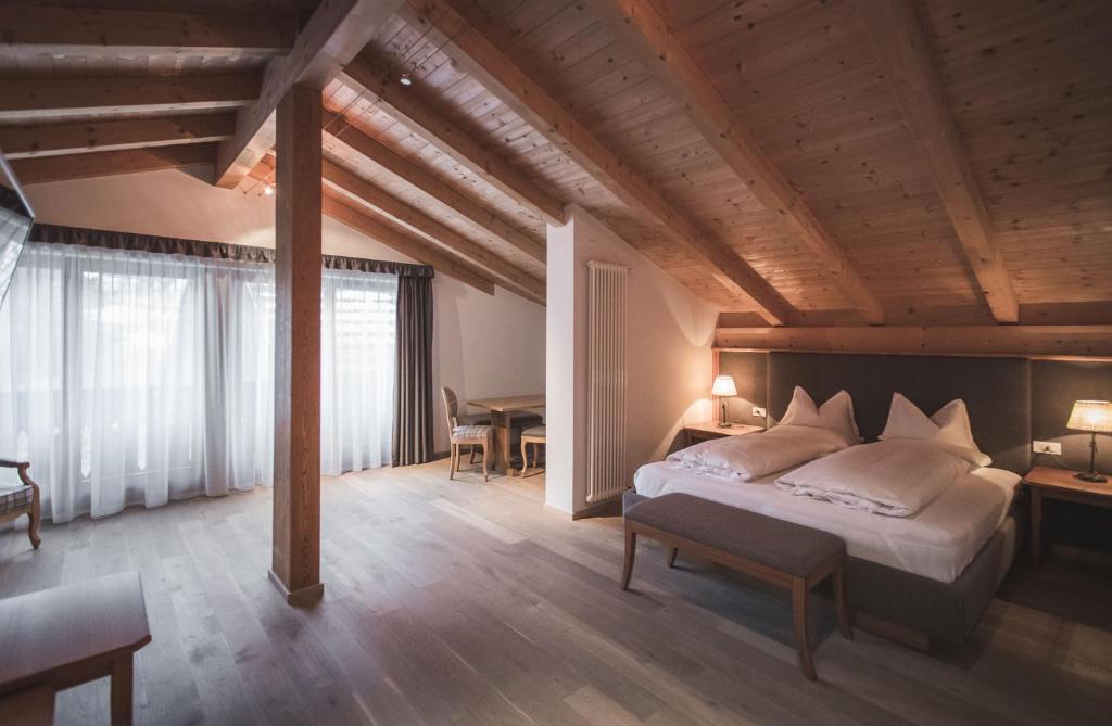 ein Schlafzimmer mit einem großen Bett und einer Holzdecke in der Unterkunft Hotel Alpenhof in Rasùn di Sotto