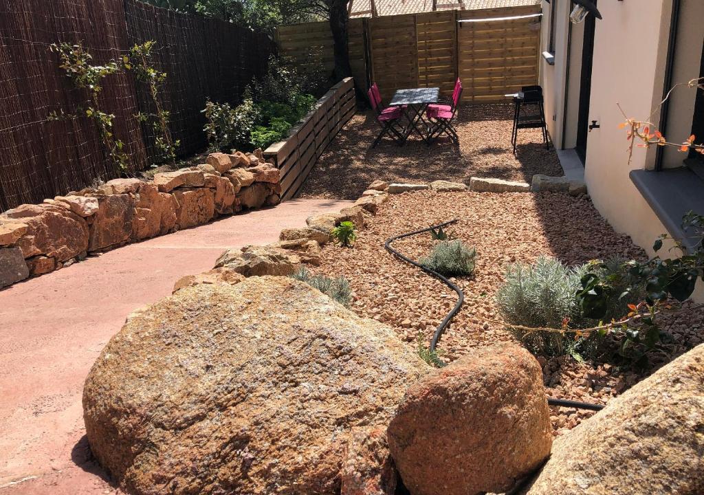 um jardim com pedras e um banco e uma parede de pedra em Chez Fred et Marie em Figari