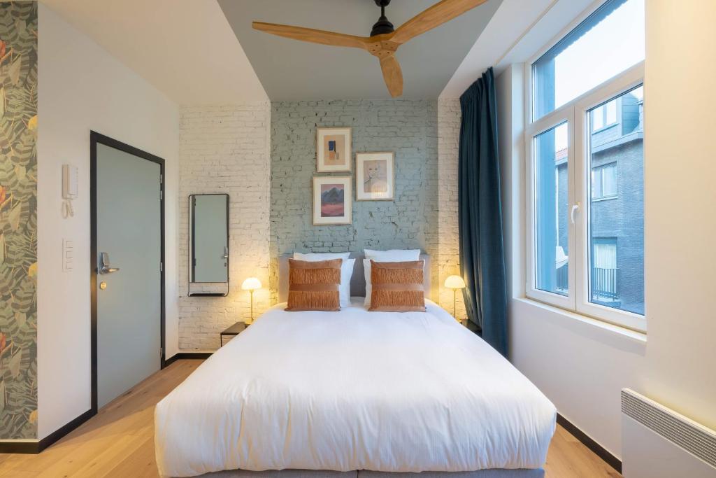 a bedroom with a large white bed and a window at The Light Blue Parrot in Antwerp