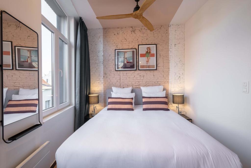 una camera da letto con un grande letto bianco con due cuscini di Pink Pigeon ad Anversa