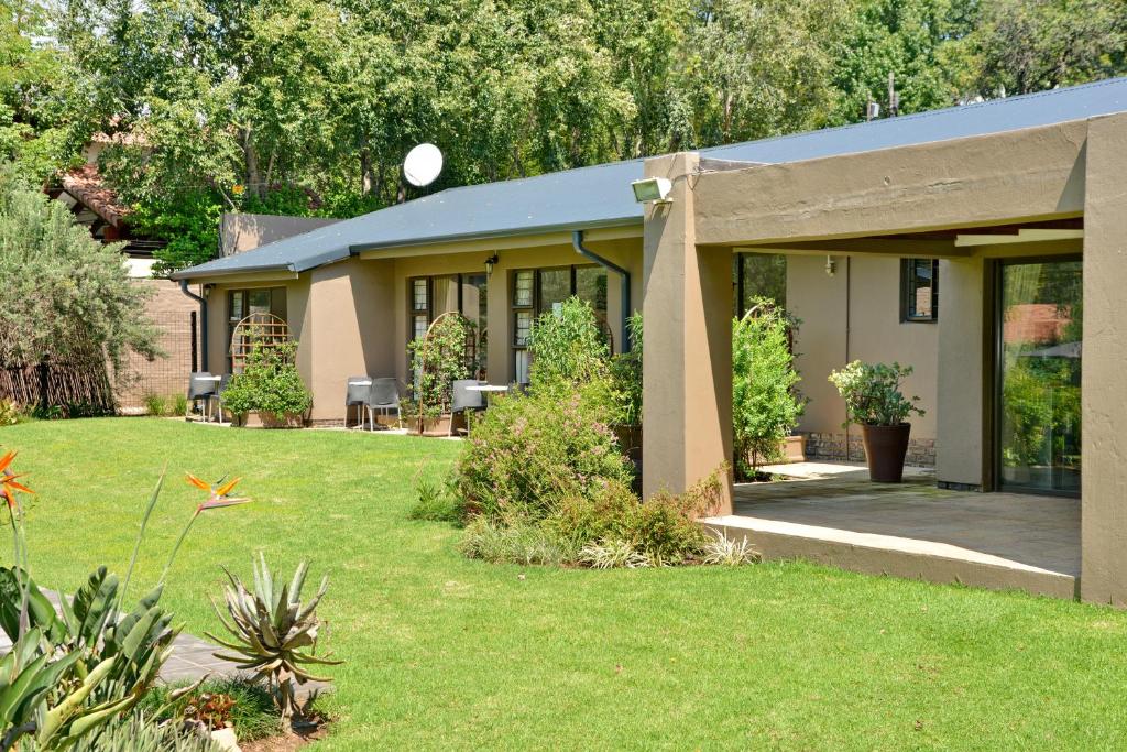 a house with a patio and a grass yard at Sand River Guest House in Johannesburg