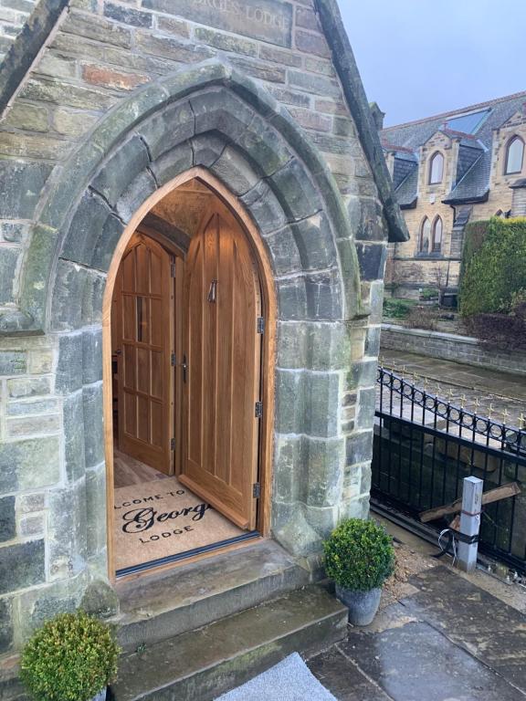 una entrada a un edificio de piedra con puerta de madera en St George’s Lodge, en Halifax