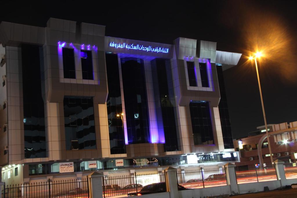 un edificio con luci viola sulla parte anteriore di notte di Al Thanaa Alraqi Furnished Apartments a Gedda