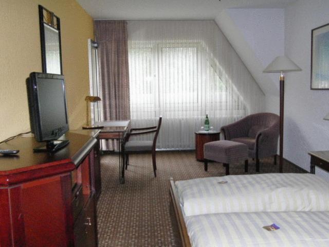 a hotel room with a bed and a desk with a television at Hotel Moselkern in Moselkern