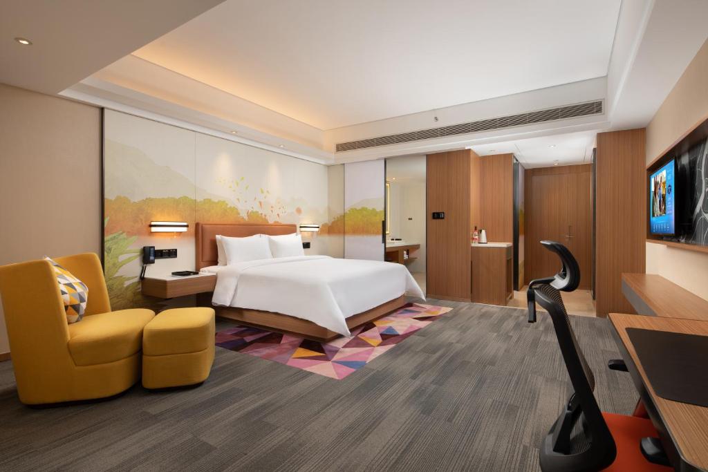een hotelkamer met een bed en een gele stoel bij Hampton by Hilton Nanhai Haikou in Haikou