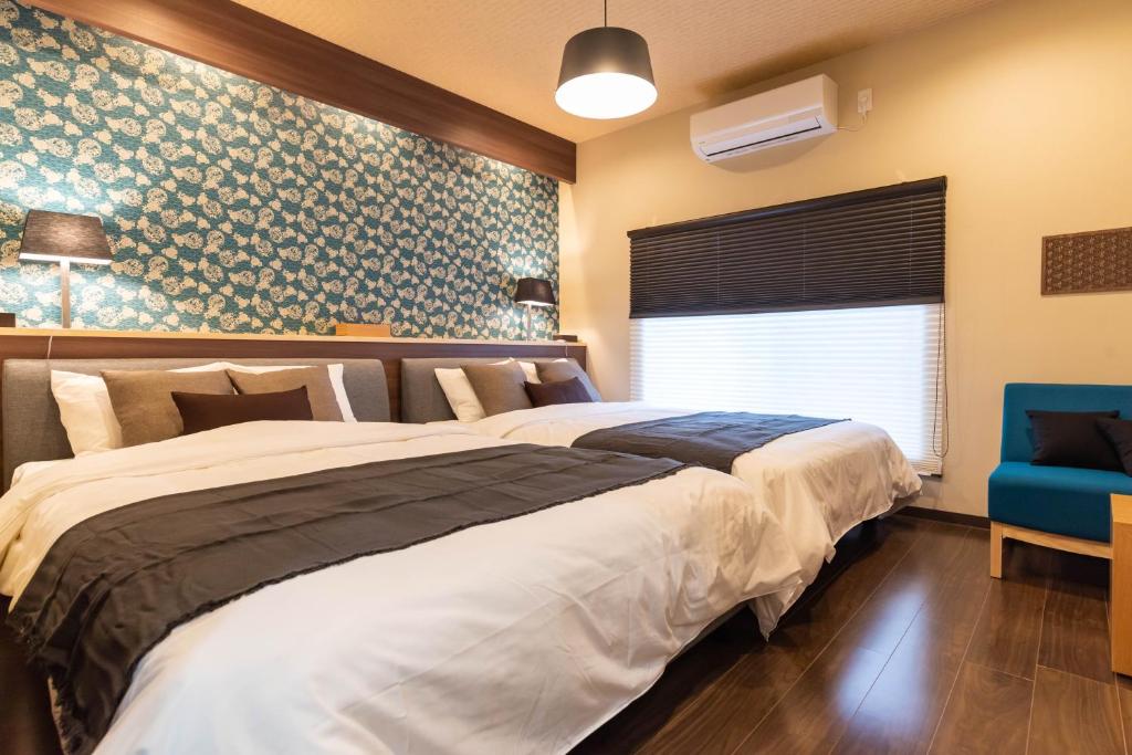 Bijou Suites Miyabi في أوساكا: غرفة نوم بسرير كبير وكرسي ازرق