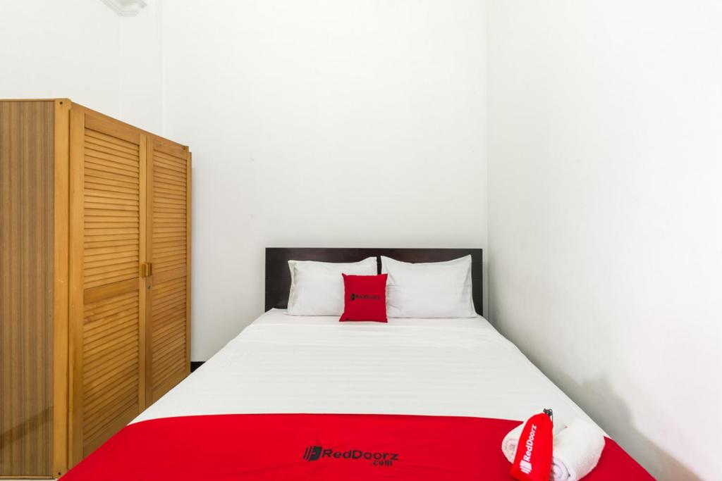 a bedroom with a bed with a red blanket at RedDoorz near Widya Mandala University in Surabaya