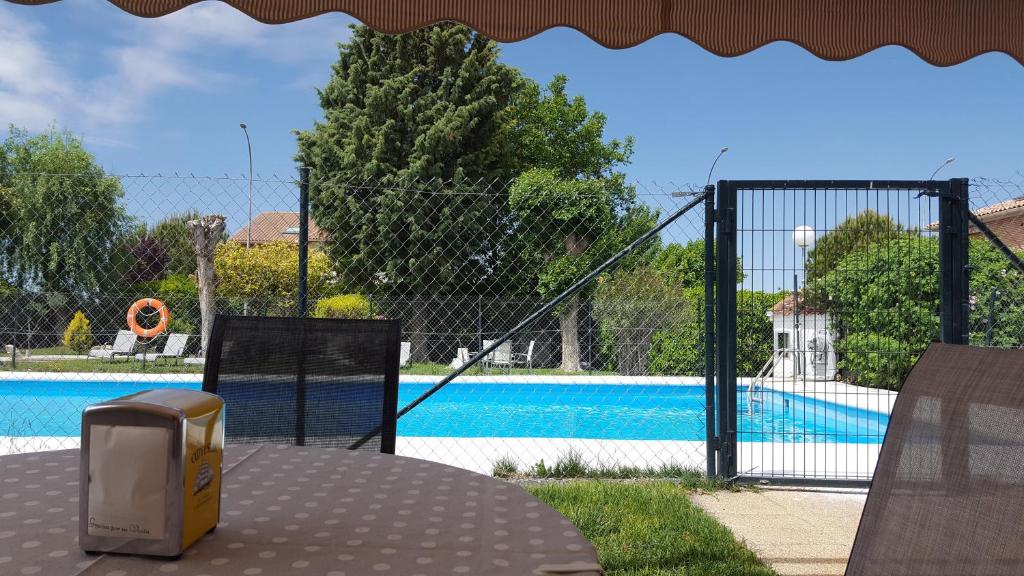 een hek met een zwembad op de achtergrond bij Hostal Restaurante Carolina in Pedrosillo el Ralo