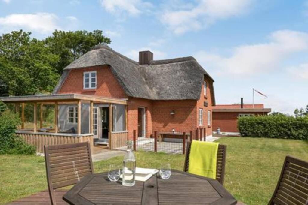 una casa con una mesa y sillas frente a ella en Thatched Holiday Home in Struer, Jutland with a view, en Struer