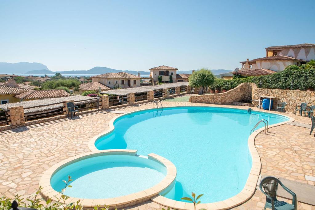 una grande piscina in un resort con un passaggio in pietra intorno ad esso di Sardegna Pittulongu Villetta vista mare a Olbia